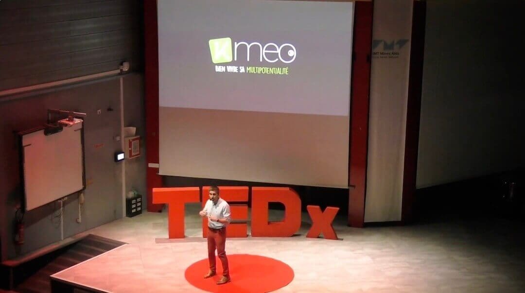 Julien tedx kmeo Speaker en pleine conférence TEDx présentant la marque Kmeo et le concept de multipotentialité sur scène.